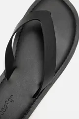 Sandalia minimalista de cuero negro, con tira delgada en el empeine y suela plana.