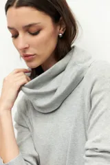 Polera color beige de cuello alto extendible, manga larga y pequeñas aberturas en los laterales.