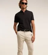 Pantalón slim color tostado, confeccionado en sarga, con cierre de botón y cremallera, y bolsillos tipo cuchillo.