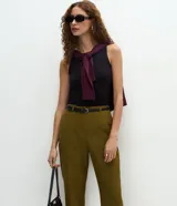 Pantalón carrot sastrero de corte recto y cintura alta, confeccionado en crepé. Presenta trabillas en la cintura, cierre tradicional y bolsillos traseros decorativos. Incluye un cinturón fino de material sintético.