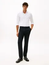 Camisa de manga larga Tommy Hilfiger confeccionada en tejido interlock, con corte slim, cuello clásico y cierre frontal de botones. Presenta el logo de la marca bordado en el pecho.