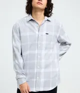 Camisa de franela de manga larga con estampado de cuadros en blanco y negro. Presenta cuello inglés, cierre frontal con botones y bolsillo en el pecho.