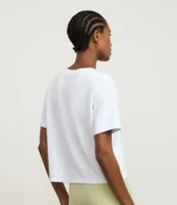 Remera cropped deportiva color blanco, confeccionada en modal, con cuello redondo, mangas cortas y estampado frontal con la palabra "League" en verde claro.