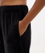 Pantalón tipo jogger de plush color negro, con cintura elástica, bolsillos laterales y puños ajustados en los tobillos.