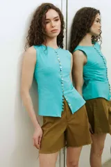 Musculosa turquesa de algodón con escote redondo y cierre frontal decorado con una hilera de múltiples botones vintage variados.