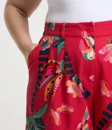 Short rojo con estampado de bananas y cocoteros, con elástico en la espalda, trabillas en la cintura, pliegues delanteros y bolsillos laterales.