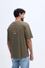 Remera oversize verde militar, confeccionada en 100% algodón, con cuello redondo y diseño relajado. Presenta un pequeño bordado frontal en tono naranja.