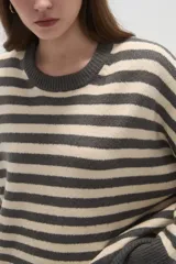 Sweater de tejido de punto con diseño de rayas horizontales en color rojo y azul marino, cuello redondo a la base y mangas largas con corte holgado.