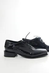 Zapato de charol negro de cuero vacuno con textura grabada tipo reptil, punta cuadrada y cordones al tono.