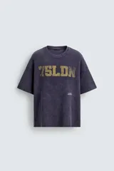 Remera de manga corta con corte relajado, confeccionada en tejido de algodón con textura tipo waffle. Presenta un efecto de lavado desgastado en color azul oscuro y estampado gráfico a contraste en el frente.