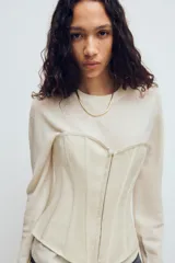 Top estilo corset de escote corazón y hombros descubiertos, con varillas interiores para estructura. Presenta cierre frontal con ganchos metálicos y ajuste posterior mediante cordones cruzados.