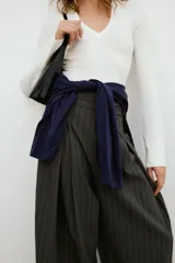 Pantalón balloon de tiro alto y diseño abuchonado, en color marrón oscuro con sutiles rayas verticales. Cuenta con pinzas y pliegues pronunciados en el delantero.