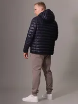 Campera acolchada con capucha de Calvin Klein, color azul marino, con cierre frontal y bolsillos laterales con cremallera. Diseño ligero y funcional con logo de la marca en el pecho.