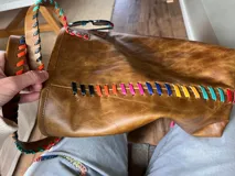 Bolso tote de cuero color marrón con costuras decorativas de hilo de colores.