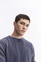 Sweater de hombre con textura waffle, color verde oliva desgastado (acid wash), cuello redondo y puños y ruedo acanalados. Presenta un pequeño logo bordado en el pecho.