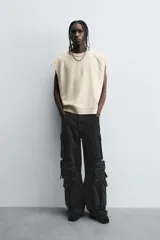 Pantalón cargo de denim lavado negro, corte relajado y tiro medio. Presenta múltiples bolsillos cargo con solapa y detalle de cierre en las perneras, además de bolsillos de vivo traseros. El bajo es ajustable con trabilla.