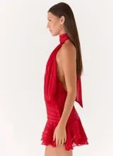 Vestido corto de satén rojo con diseño de cuello halter, cuerpo holgado y falda con volados y cintura elástica fruncida.