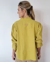 Blusa de algodón con cuello mao y volados, mangas largas con puños elásticos y corte holgado.