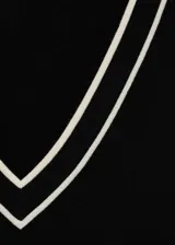 Jersey de punto fino de manga larga en color negro, con cuello en V y detalles de líneas blancas en contraste en el cuello y los puños.