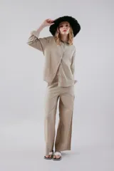 Pantalón de vestir color beige, de corte recto y tiro alto, con bolsillos laterales y cierre frontal con botón y cremallera.