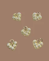 Capa de paño color rojo con corte amplio y caída natural. Presenta detalles de dijes metálicos en baño de oro distribuidos en la espalda y una etiqueta de cuero con el logo de la marca en la parte superior.