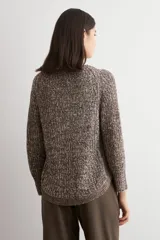 Sweater de punto con textura jaspeada en tonos marrones, de corte recto, cuello redondo y mangas largas. Presenta un diseño con ruedo curvo.