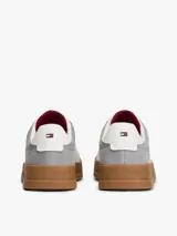 Zapatillas de tenis Tommy Hilfiger de corte bajo, confeccionadas en piel nobuk con paneles de texturas mixtas en blanco y gris. Presentan suela de goma color caramelo, cierre con cordones y detalles distintivos de la marca en la lengüeta, lateral y talón.
