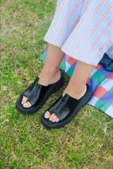 Sandalias plataformas negras con tira ancha en el empeine y separación para el dedo, suela gruesa y diseño abierto.