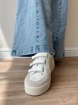 Zapatillas blancas de cuero con detalles en cuero gamuzado color beige en la puntera y ajuste con velcro. Presenta detalle de cuero con estampado reptil en el talón.