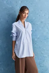 Camisa de calce relajado color celeste, con escote en V y cuello mao, mangas largas y largo extendido.