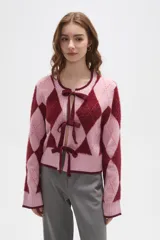 Cardigan de punto con diseño de rombos en tonos rosa y bordó. Presenta cierre frontal mediante lazos anudados, cuello redondo y mangas largas con puños acanalados.