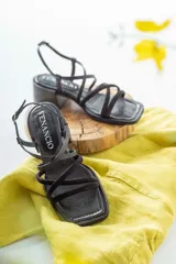 Sandalias de cuero negro con tiras finas cruzadas, taco cuadrado y hebilla lateral.