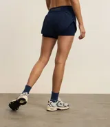 Bermuda deportiva tipo runner de microfibra color azul marino, con cintura elástica, bolsillo con cierre y diseño holgado con bajo redondeado.