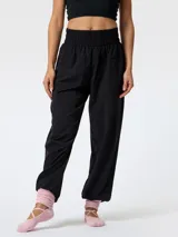 Pantalón de microfibra negro, de corte estilo bombacho y silueta relajada, con cintura y puños elásticos fruncidos. Presenta costuras frontales verticales y bolsillos funcionales.
