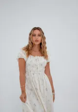 Vestido corto color crema con estampado floral, escote cuadrado con lazo ajustable, mangas cortas abullonadas y corte princesa.