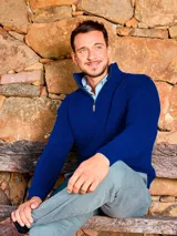 Buzo de punto con medio cierre frontal, confeccionado en lana lambswool. Presenta cuello alto, mangas largas con puños acanalados y diseño clásico de ajuste cómodo.