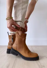 Bota de cuero color marrón con suela de goma negra, cierre lateral y pulsera desmontable con hebilla.