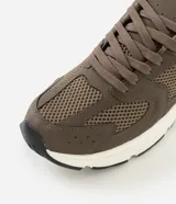 Championes de estilo deportivo urbano, confeccionados en material sintético con paneles de malla y detalles texturizados. Presentan un diseño robusto con suela de goma gruesa en color blanco y base de rodadura negra, cierre mediante cordones y forro interior acolchado.