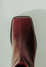 Bota de caña media confeccionada en cuero natural color bordó, con diseño minimalista, punta cuadrada y taco ancho de altura media.
