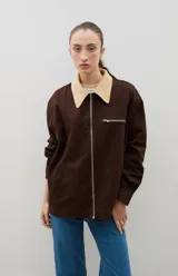 Campera de jean azul oscuro con cuello de pana en color crema. Presenta cierre frontal metálico, bolsillo con cierre en el pecho y bolsillos laterales. Diseño de corte holgado con mangas largas.