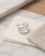 Set de tres anillos de acero plateado con diseños variados: dos lisos con banda delgada y uno central con textura trenzada o de cadena.