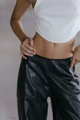 Pantalón cargo de ecocuero negro, de corte holgado y tiro medio-alto. Presenta bolsillos laterales tipo cargo y costuras visibles a lo largo de las piernas.