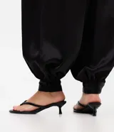 Pantalón aladín negro de satén, con diseño de caída amplia, cintura ajustada y botamanga con puño elástico.