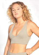 Top deportivo o bralette color beige claro, de tejido acanalado (rib) elástico. Presenta escote en V profundo y breteles anchos fijos. Posee una banda inferior ancha y elástica para mayor sujeción.