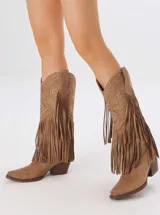 Botas de estilo western confeccionadas en gamuza color tostado, con caña media adornada con flecos largos, bordados decorativos y apliques de tachas metálicas. Presentan taco cuadrado y punta fina.