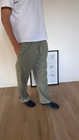 Pantalón de franela para hombre con diseño a cuadros escoceses en tonos verde y negro, cintura elástica con cordón ajustable y bolsillos laterales.