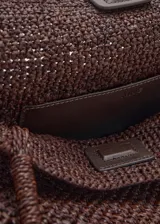 Bolso tipo shopper color marrón, confeccionado en paja trenzada con dos asas largas para llevar al hombro.
