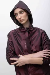 Capucha deportiva color borgoña, confeccionada en tafeta tornasolada. Se ajusta con dos tiras que pueden anudarse formando un lazo.