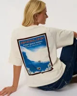 Remera Rip Curl de manga corta, color beige, con diseño boxy y estampado gráfico en la espalda de la competencia de surf Rip Curl Cup en Sunset Beach, Hawaii.