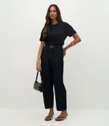 Camiseta blanca de algodón con cuello redondo y mangas cortas, decorada con pequeños lazos brillantes en los laterales de las mangas.